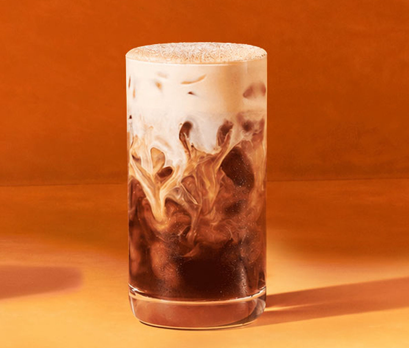 An iced coffee drink with a thick layer of pumpkin cream cold foam.
